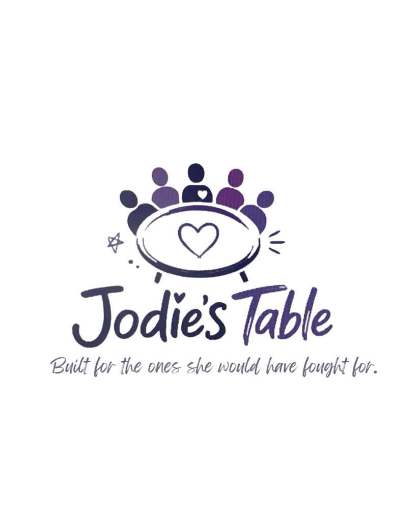 A Table with 5 outlined people sitting at it. A heart in the middle of the table. Jodie's Table, built for the ones she would have fought for. 